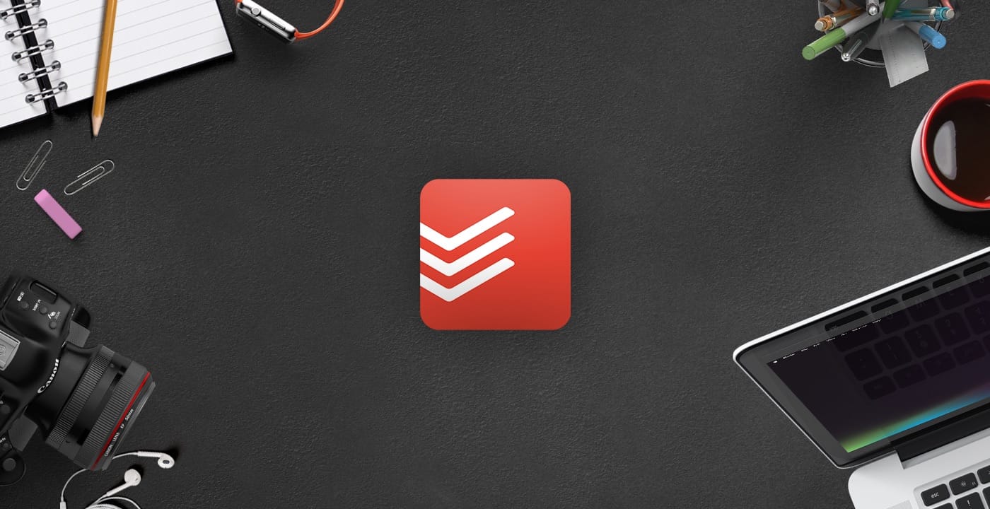Todoist logo shown on a desk surrounded by tech items
