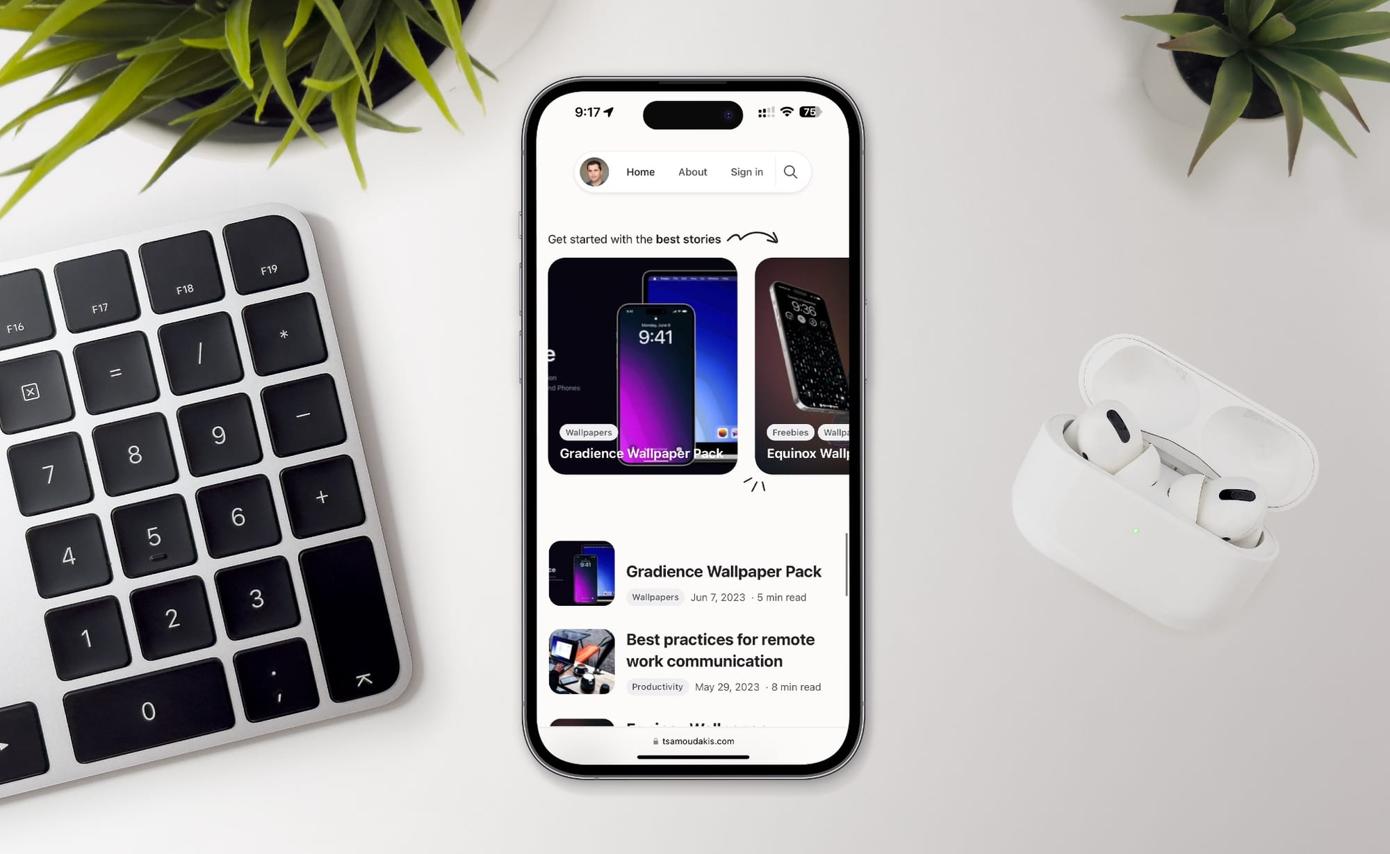 iPhone showing this website and surrounded by an Apple keyboard and AirPods